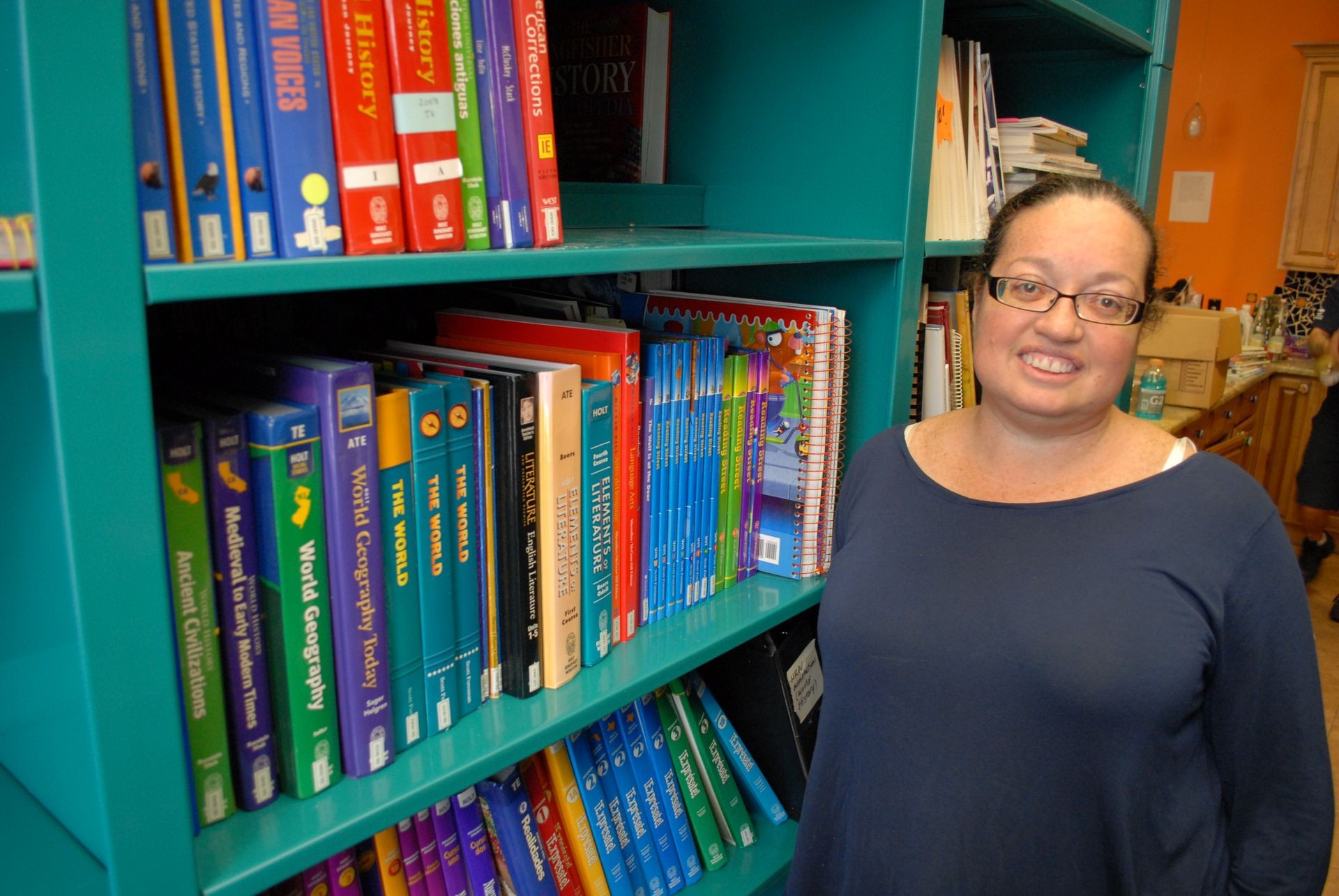 Bookshelf filled with educational textbooks and workbooks in a classroom or library setting.