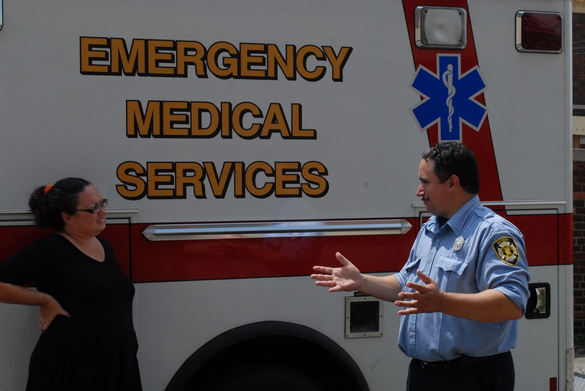 Emergency medical services worker talking to a woman beside an EMT vehicle.