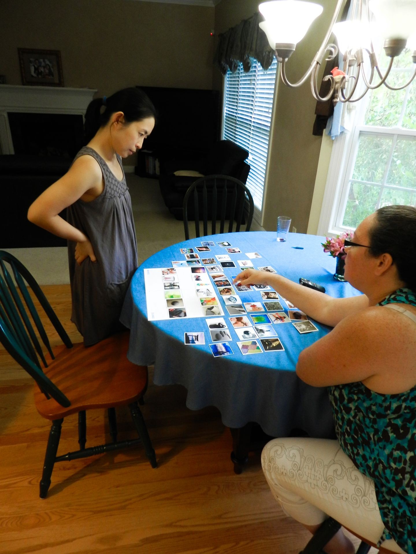 Two people at a table with photo cards spread out, discussing and pointing at the images.