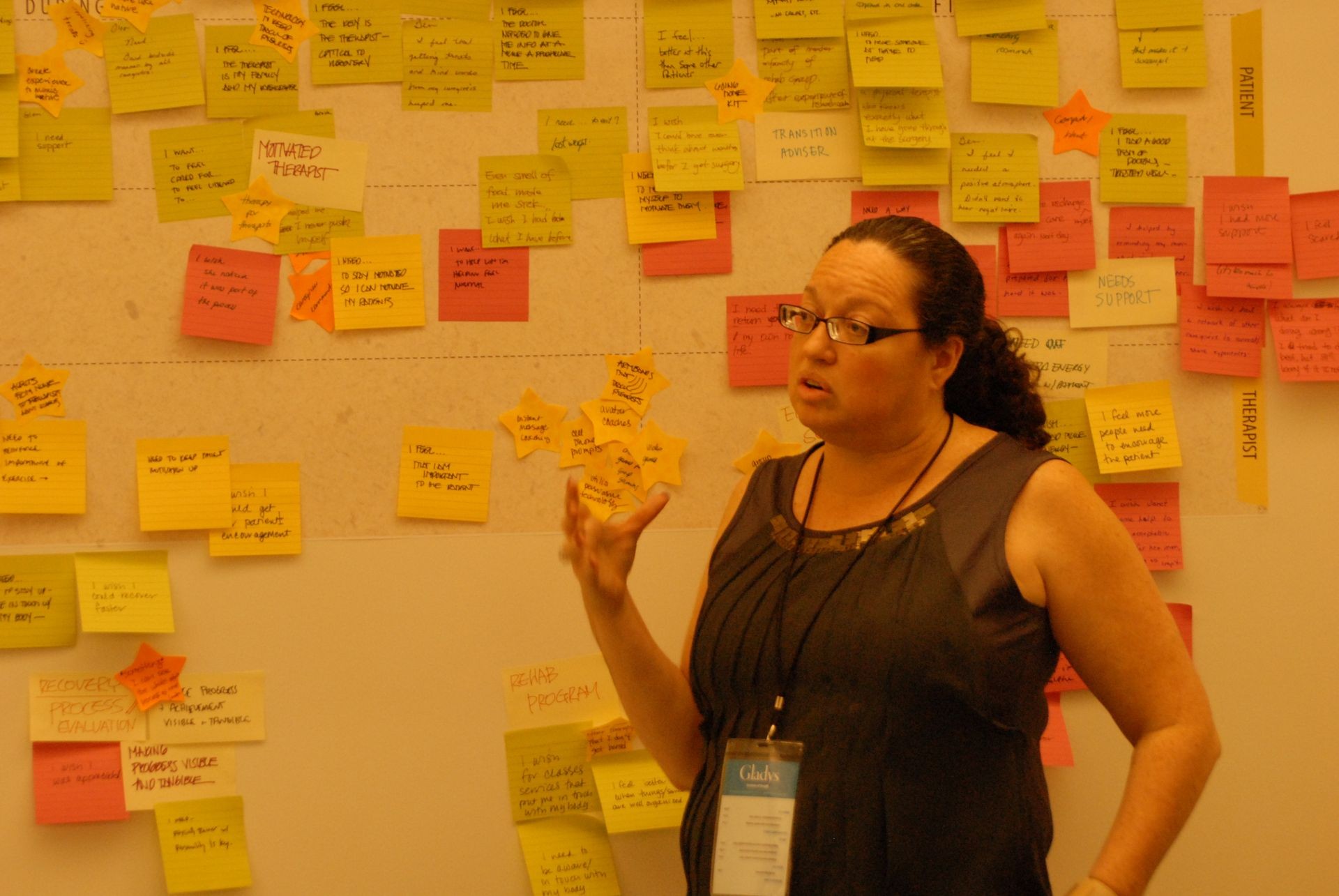 Person giving a presentation in front of a board covered with various colorful sticky notes and comments.