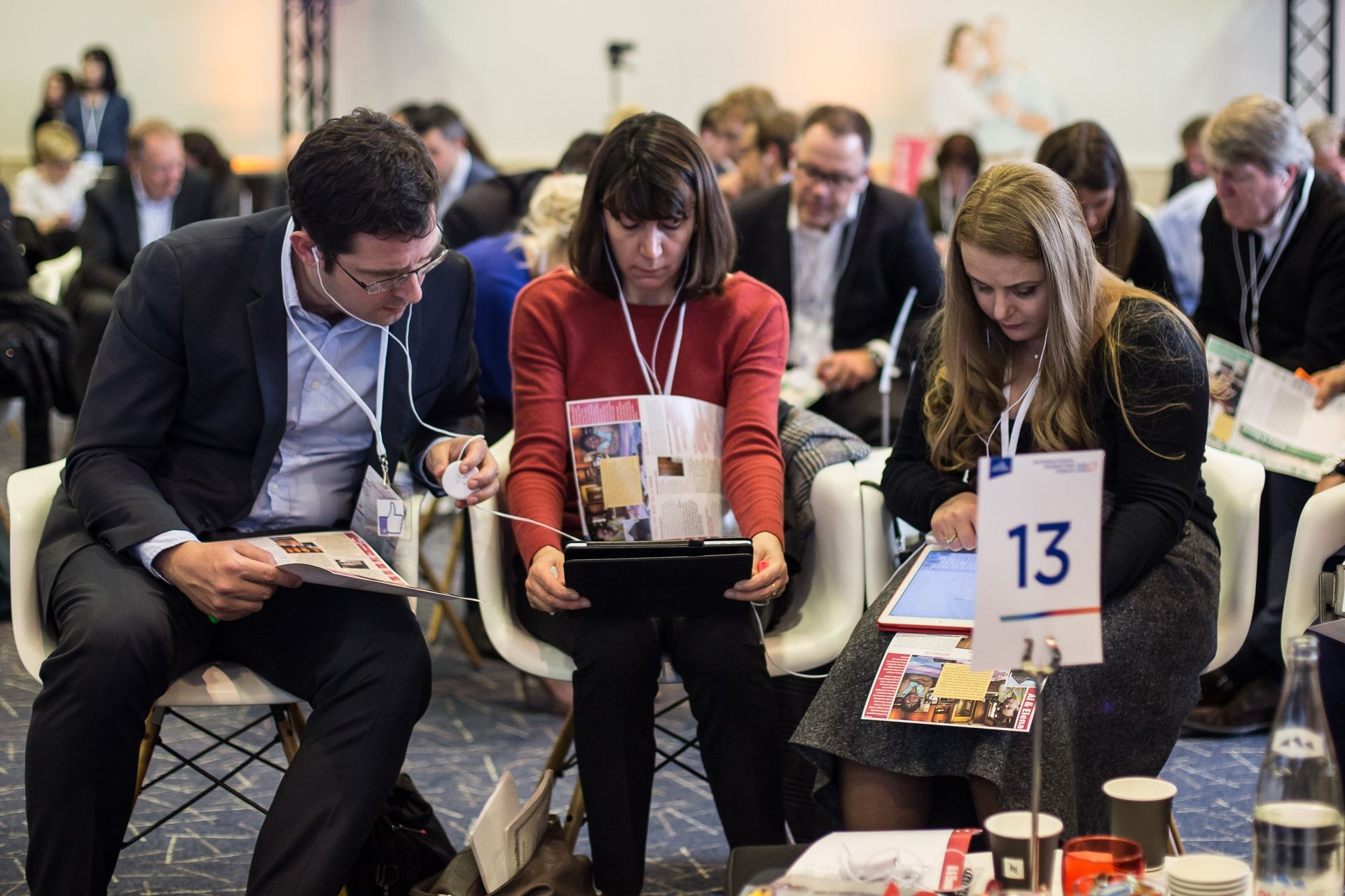 People in a conference setting using tablets and reading materials.